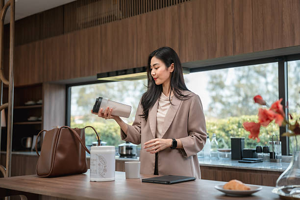Businesswoman preparing a protein shake in her kitchen before heading to work, fueling her body with a nutritious boost to start her productive day