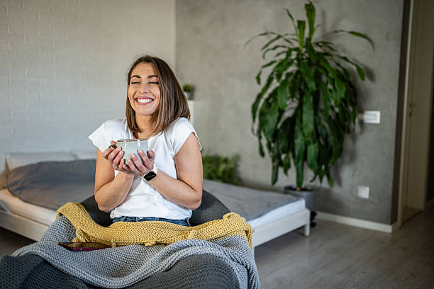 istock Young woman smiling and drinking tea at home 2220891241
