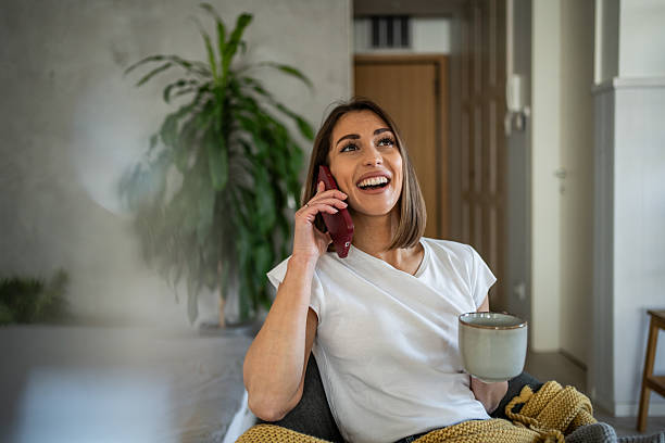 istock Young woman relaxing on sofa, talking on phone and drinking tea 2220891432