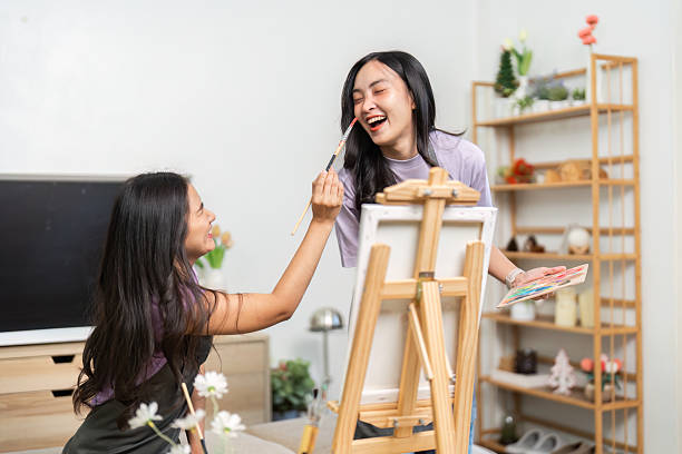 istock Playful Art Interaction. Two women having fun while painting each other. 2220893505