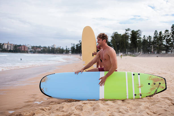 Male surfer is preparing to face the ocean at Sydney’s famous Manly Beach, ready to ride the waves.