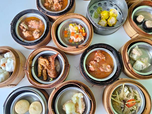 chinese food, cuisine, close up overhead view of various dim sum dishes, neatly arranged in traditional classic bamboo steamers and small metal bowls on white surface background,highlights the diverse textures and colorful food order