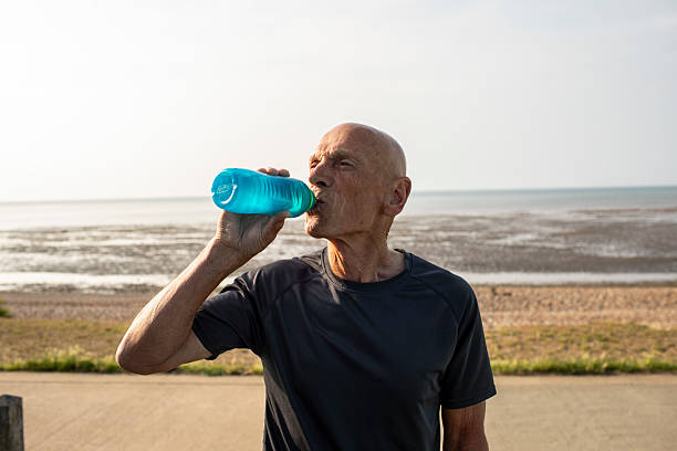 istock Active senior man drinking from a water bottle by the coast 2220898235