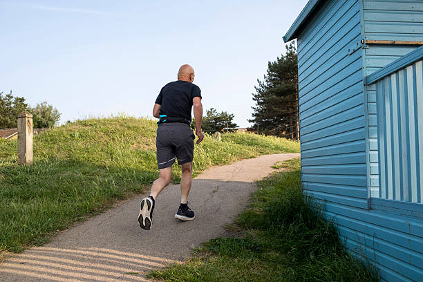 Part of a series: Active senior man running and keeping fit by the coast at Whitstable, Kent, England at the end of a summer's day.