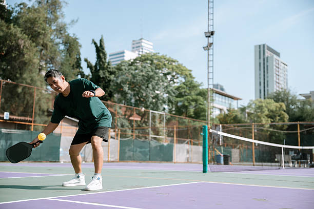 istock Relaxed mature man serving a pickleball with his paddle 2220898298