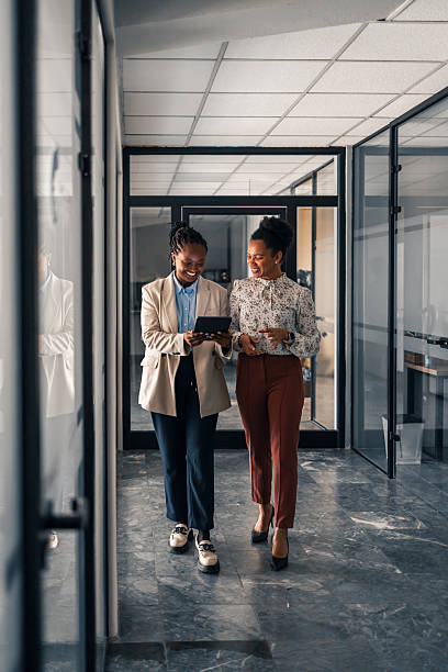 istock Two Professionals Walking Through Office Corridor and Discussing on Digital Tablet 2220899342
