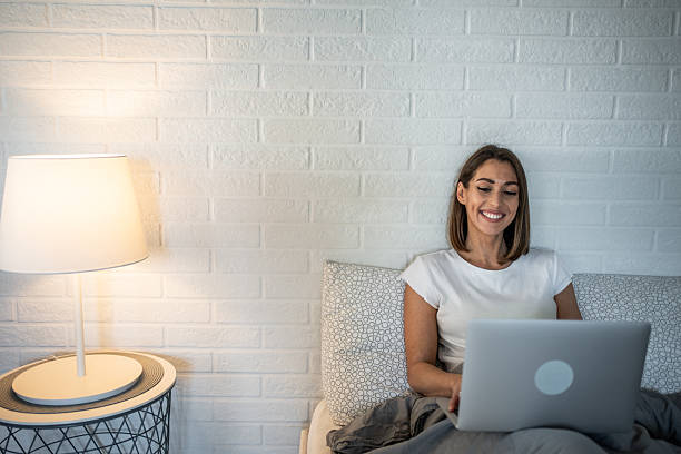 istock Young woman working from home using laptop in bed smiling 2220902545
