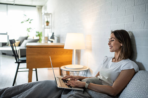 istock Young woman working remotely from her cozy bed with laptop 2220903067