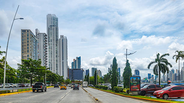 Panama City, Panama - June 12, 2025: Cars driving in a city avenue with cityscape of the modern downtown in the distance. Point of view image