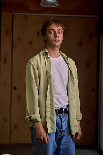 istock Casual young man standing indoors with open shirt and thoughtful expression 2220908893