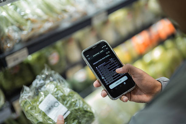 Close-up shot of a man using his smartphone to check the ingredient list while selecting groceries from the shelf, carefully choosing the best ingredients for his home-cooked meals