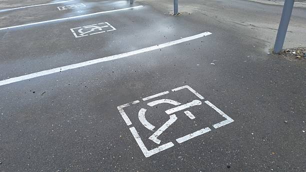 istock Accessible parking spots with handicap symbols on wet asphalt in empty lot 2220910188