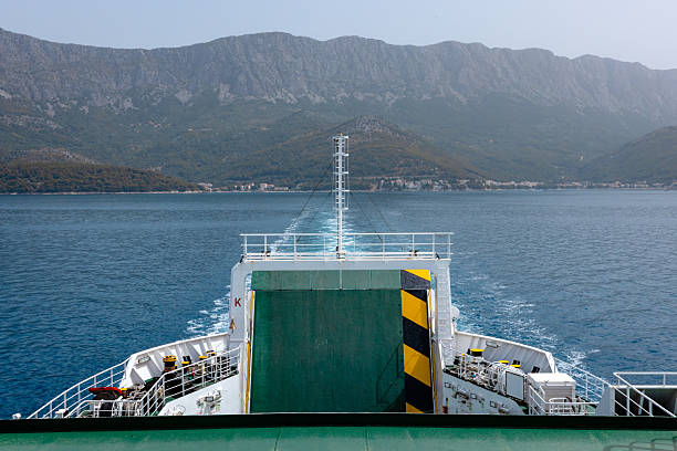 A tranquil summer view from the top deck of a Croatian ferry, featuring empty yellow seats, a green-painted deck, and a vast blue sea stretching toward the rugged Croatian coastline. The composition highlights the calm yet adventurous spirit of maritime travel, ideal for tourism, transportation, and vacation themes.