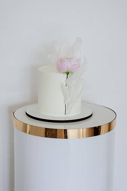 istock Minimalist white cake adorned with a delicate pink flower and artistic translucent elements. 2220921908