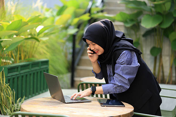 istock Female Hijab Working Mom, Working with Laptop While Making Phone Call 2220925637