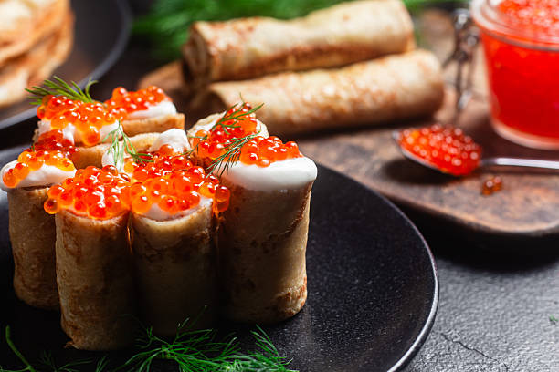 istock blini with red caviar in a black plate on the table. Thin pancakes. Carnival 2220926508