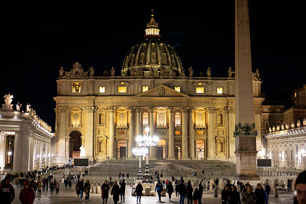 The majestic St. Peter’s Basilica shines under the night sky in Vatican City, surrounded by visitors in awe of its beauty