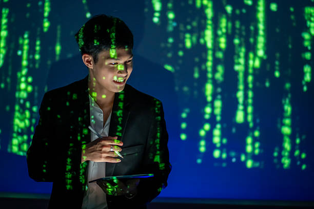 istock New generation Asian business people use laptops, tablets and smartphones while looking at UV light on a projector screen and collaborating over the internet on laptops, modern networks. 2220930440