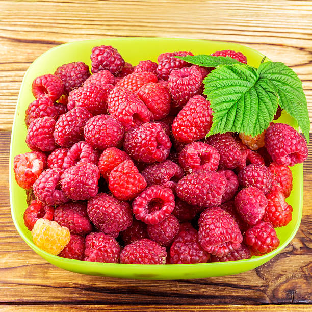 Bowl full of ripe raspberries on rustic wooden table