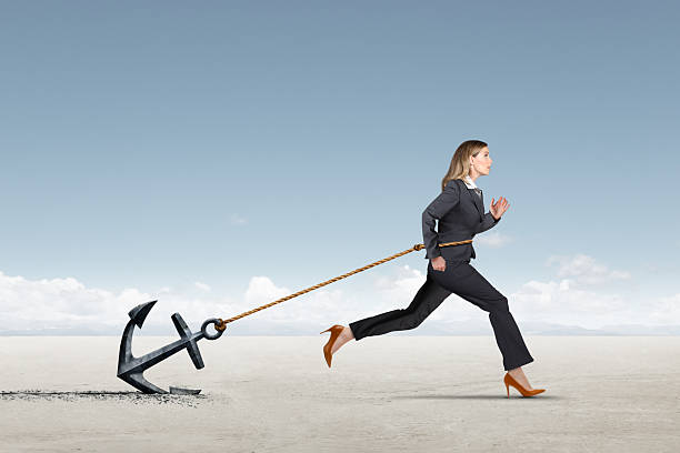 istock Businessowman Struggling To Run While Dragging An Anchor 2220932171
