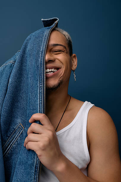 Young man showcases vibrant style with denim flair against a striking blue backdrop