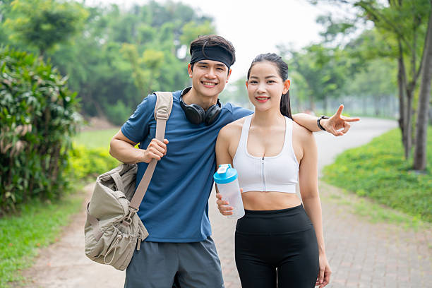 istock Fitness buddies smiling together after a workout on a paved park path with lush greenery 2220933572
