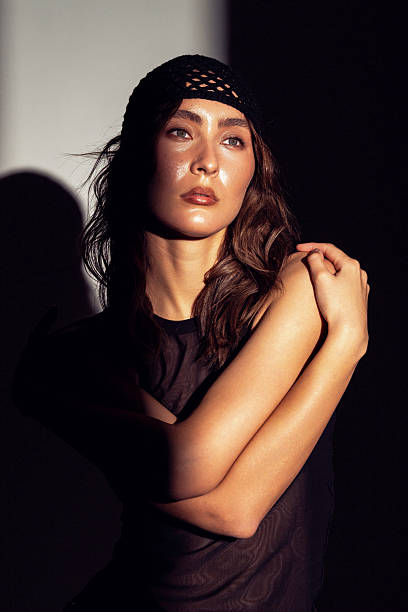 A stunning Asian woman showcases graceful poses in artistic, contrasting lighting indoors.
