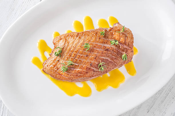 istock Whole Crispy Duck Breast on Mustard Lemon Honey Sauce in White Plate 2220944104