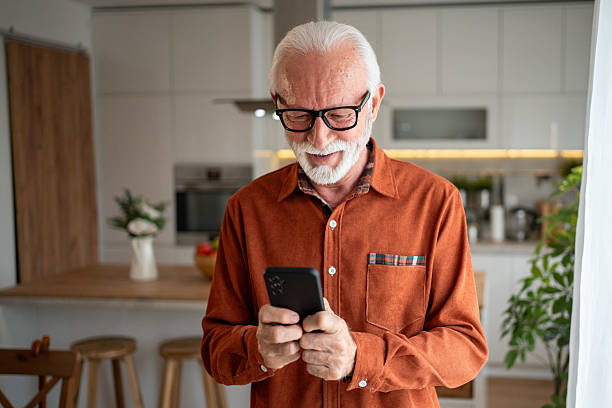 istock Happy senior man using smartphone at home in the kitchen 2220950753