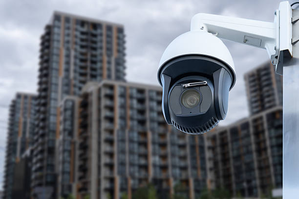 istock Panoramic view of CCTV surveillance camera with blurred apartment building background with copy space for background banner. 2220951840