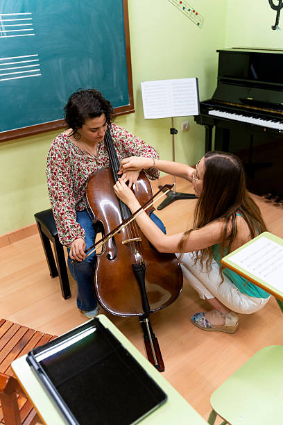 istock Music teacher helping student playing cello in classroom 2220953099