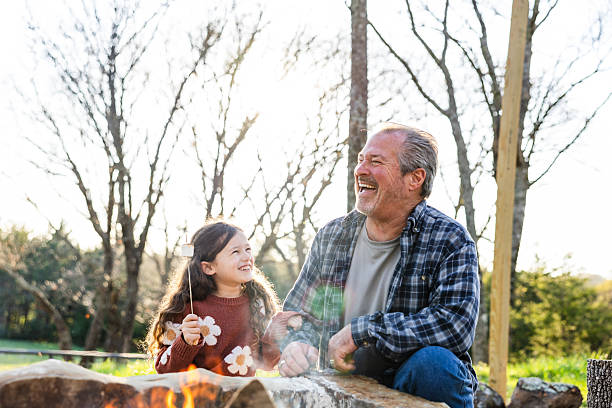 istock Grandfather and granddaughter roasting marshmallows by bonfire 2220957967