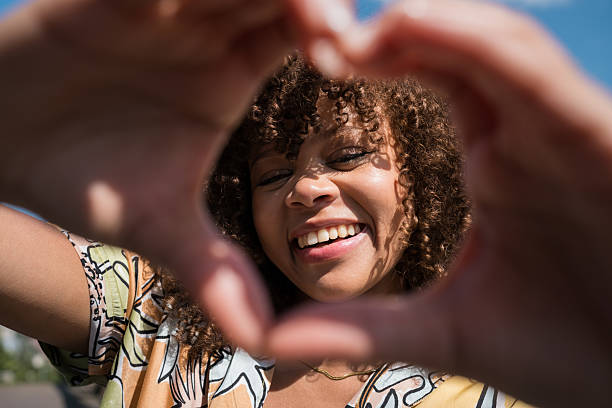 istock Young woman making heart shape with hands and smiling at camera 2220965251