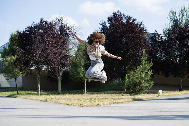 istock Young woman jumping with joy in a park 2220965820