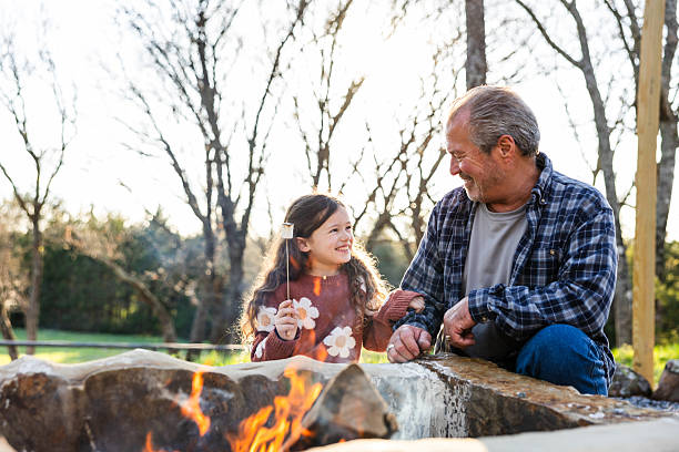 istock Grandfather and Granddaughter Roasting Marshmallows by a Fire Pit 2220971057