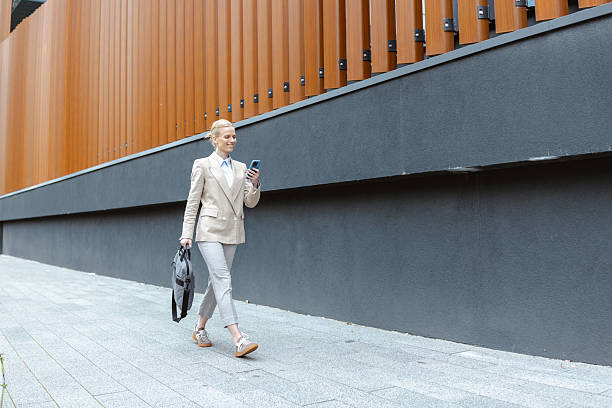 istock Professional woman walking confidently holding her phone and bag 2220977886