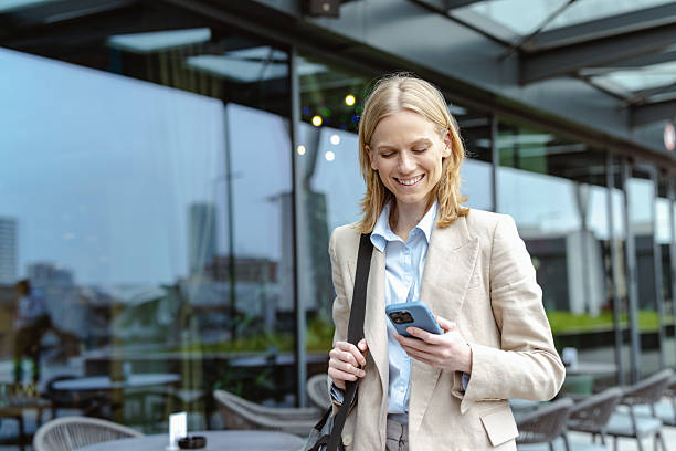 istock Young professional walking outdoors and smiling while checking her smartphone 2220978220