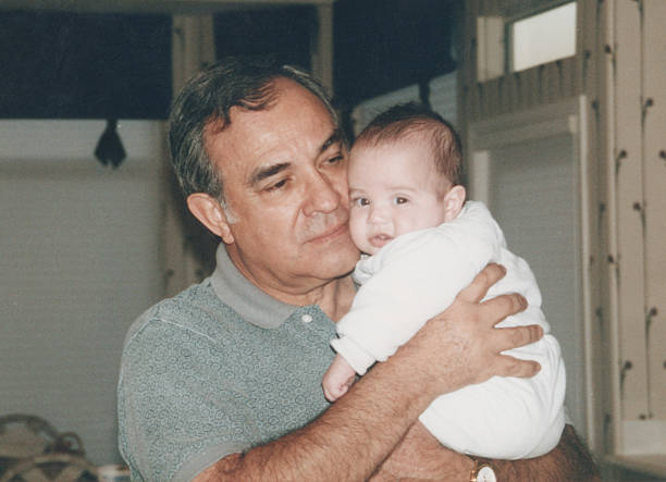 istock Hispanic mature man holding his grandson posing inside his home 2220980569