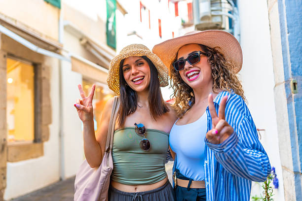 istock Two young women showing peace sign while walking down the street 2220982019