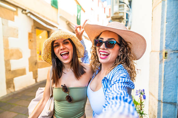 istock Two happy tourists taking a selfie while walking in a city center 2220982023