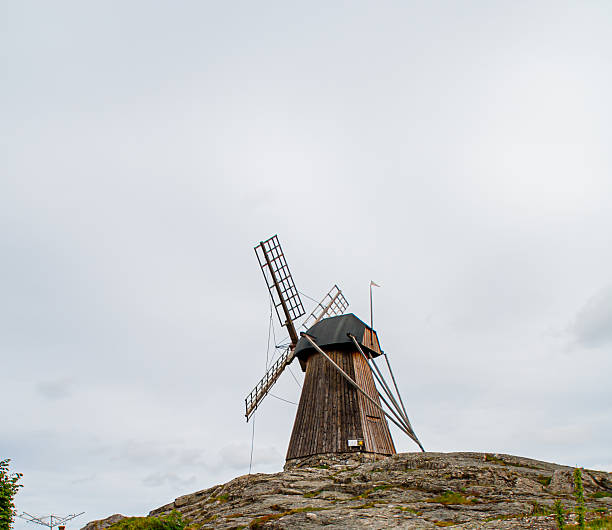 Evening view of a wind turbine with forests and a paper mill in the background.