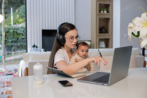 istock Young mother working from home on laptop while holding child on lap 2220985010