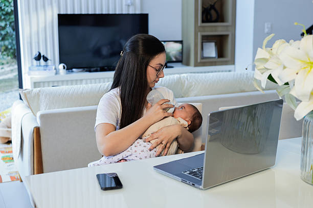 istock Young mother working from home on laptop while holding child on lap 2220985050