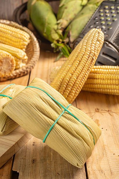 istock Green corn and pamonha, cobs of green corn, cheese and pamonha and accessories on a rustic wooden table, selective focus 2220986617