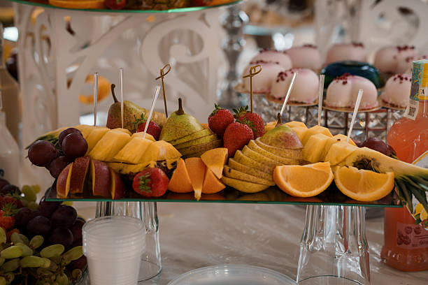 Elegant Fruit Display at a Wedding Reception: Oranges, Strawberries, Pears, Grapes on Tiered Stand, Pink Decor, Glassware