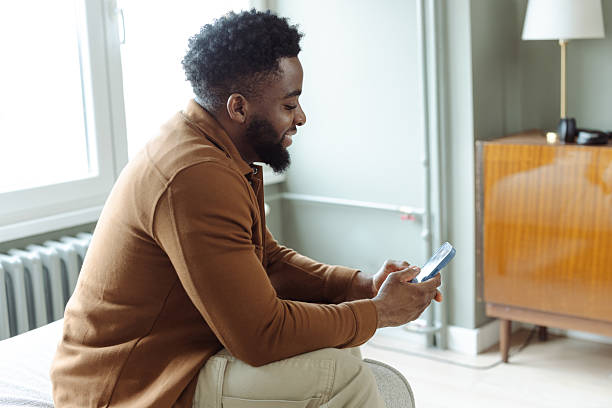 istock Man sitting indoors using smartphone while smiling and enjoying leisure moments 2220992809
