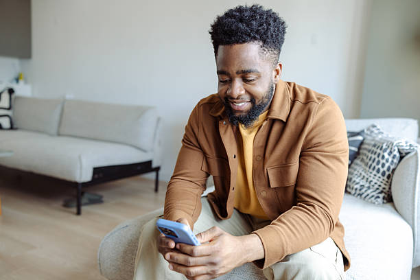 istock Smiling man browsing on smartphone while seated in a cozy living room 2220992900