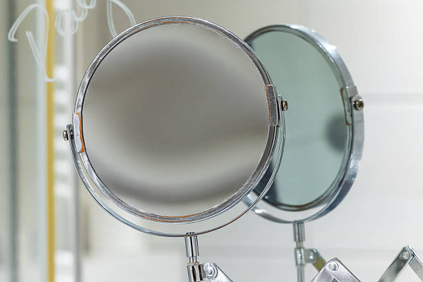 Round bathroom magnifying mirror mounted to the wall with a pantograph.