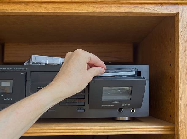 Sliding cassette tape into stereo audio cassette deck.