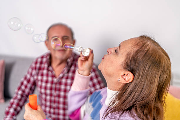 istock Senior couple playing with soap bubbles at home 2221002854